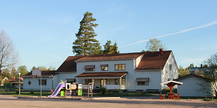 Bild på förskolan Prästkragen, vitt hus med lekpark framför