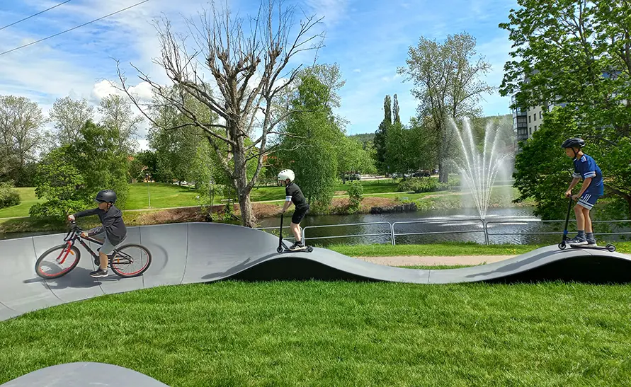 Tre barn som åker cykel på en pumptrackbana