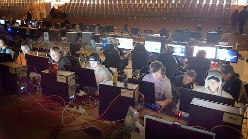 Bild på personer som sitter vid datorer i en stor hall